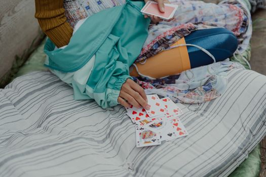 Close-up of an individual playing cards while wearing vibrant, layered clothing.