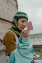 Woman in Green and Yellow Hijab Holding White Smartphone