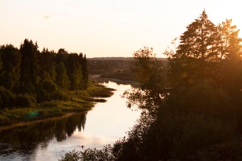 Free A tranquil river winding through lush forests in Velsk, captured at sunset with golden hues. Stock Photo