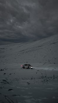 Capture of a lone pickup truck navigating a snowy road under a moody winter sky in Kayseri, Türkiye.