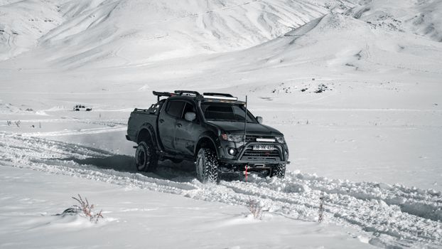 4x4 vehicle navigating a snow-covered mountain landscape in winter.