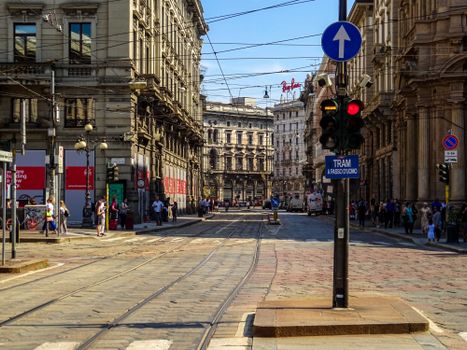 View of a busy street in Milan, Italy showcasing historic architecture and tram lines.