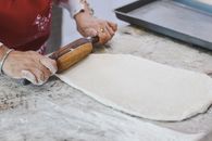 Person in White Long Sleeve Shirt Holding Brown Wooden Rolling Pin