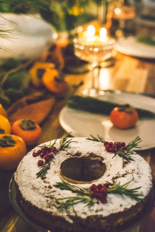 Free Rustic holiday cake with powdered sugar and fruit on a cozy candlelit table. Stock Photo