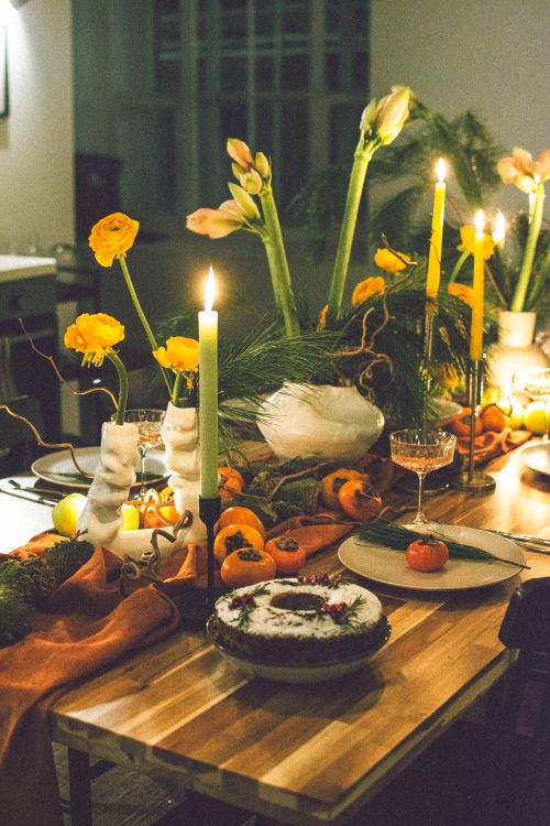 Free A warm, candlelit dinner setting with a vibrant floral arrangement and dessert on the table. Stock Photo