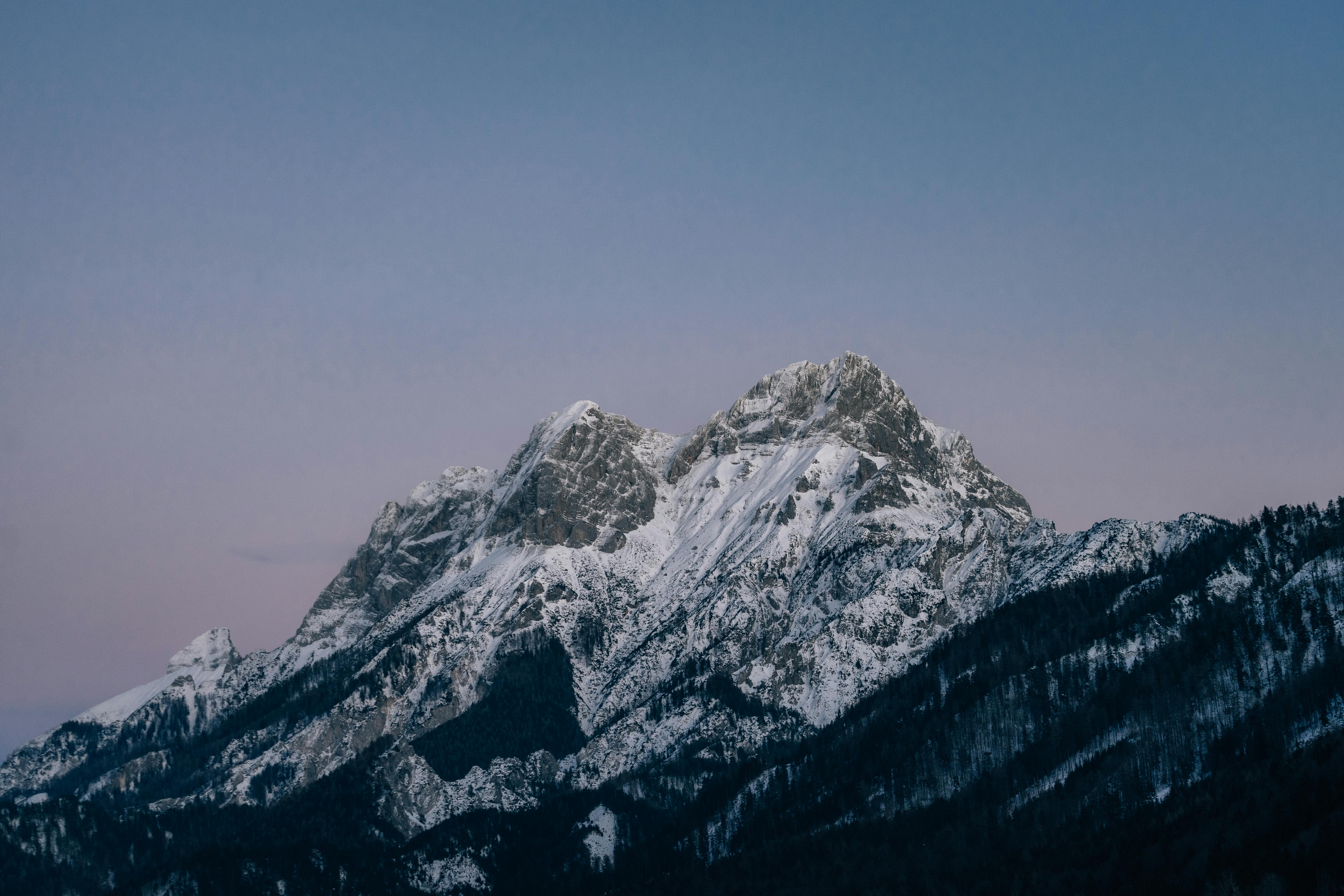 Breathtaking snow-capped mountain under a clear sky during twilight, showcasing natural beauty and tranquility.