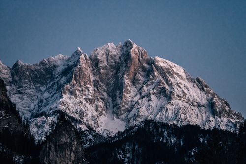 Free A stunning view of a snowcapped mountain peak under a clear blue sky during sunrise. Stock Photo