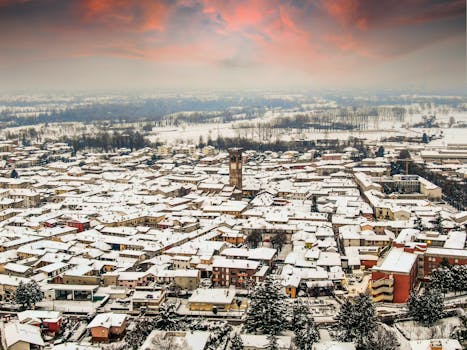 Aerial view of snowy rooftops in Rivolta d'Adda, Lombardy under vibrant winter skies.