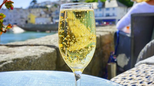 Прозрачный бокал для шампанского с желтой жидкостью на круглом столе из синего стекла