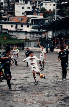 Dynamic scene of a soccer game on a muddy field in Neira, Colombia, showcasing teamwork under challenging conditions.