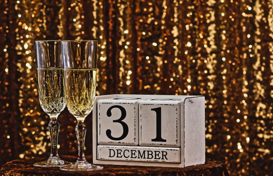 Sparkling champagne glasses with December 31st calendar block for New Year's Eve party.