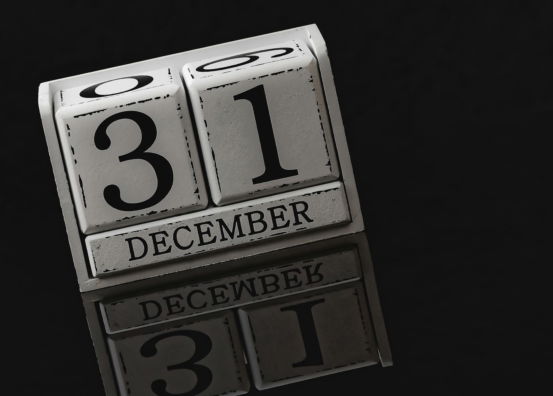 Close-up of a perpetual calendar displaying December 31st, reflecting on a black surface.