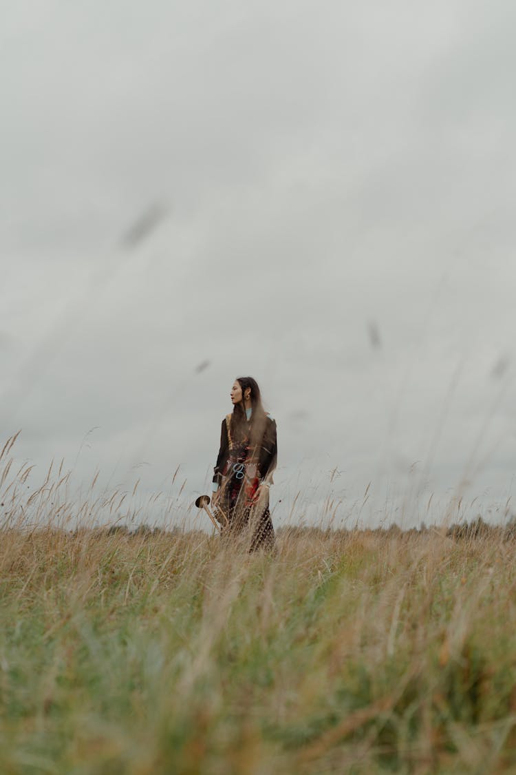 Woman Standing On Grass Field Holding A Trumpet