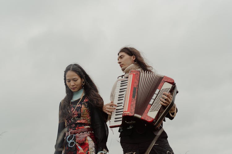 Man Playing An Accordion Beside The Woman