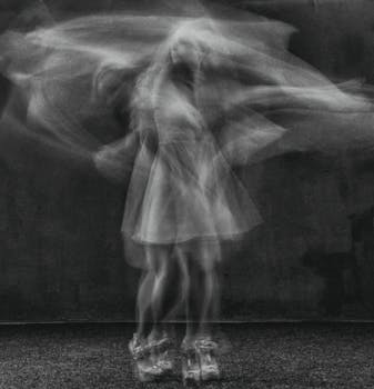 Abstract image of a woman dancing, captured in motion blur, creating an ethereal black and white effect.
