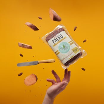 Creative concept of paleo bread and ingredients suspended mid-air against a yellow background.