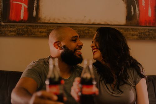 Free A joyful couple shares a soda and laughter indoors, capturing the essence of love and togetherness. Stock Photo