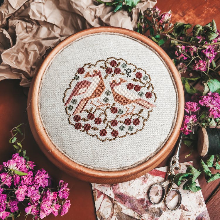 A Cross Stitch In A Round Wooden Frame 