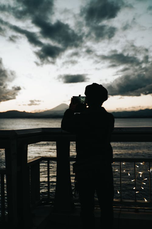 Silhouette of Person on Balcony Holding a Cellphone