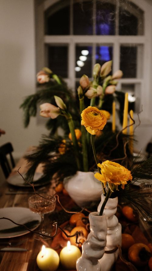 Free An elegant indoor table setting with vibrant flowers and glowing candles, perfect for a cozy evening. Stock Photo