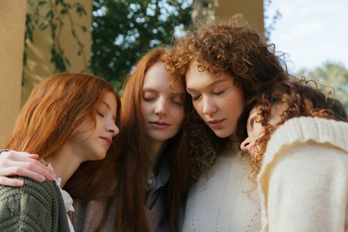 Free Four young women with closed eyes embracing outdoors during summer, symbolizing friendship and togetherness. Stock Photo