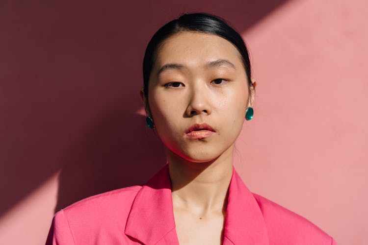 Young Woman With Green Earrings Wearing Pink Jacket