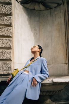 Fashionable woman posing in a light blue blazer outdoors.