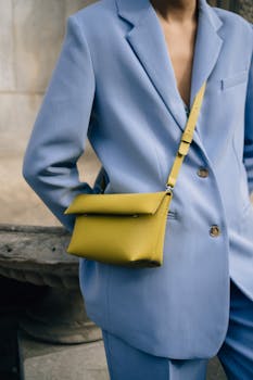 A fashionable person in a blue suit carrying a yellow handbag. Perfect for style inspiration.