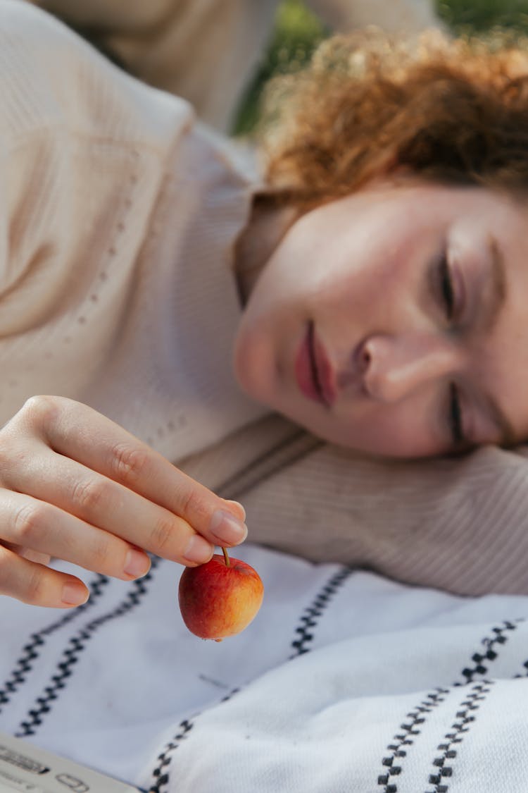 Woman Lying And Holding Up An Apple