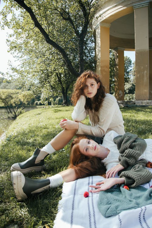 Women sitting and Lying Down on Blanket on Grass