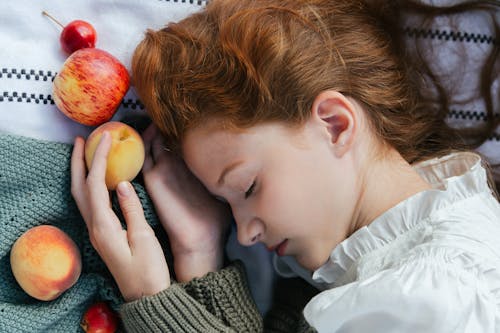 Woman Lying Down with Closed Eyes and Holding Apple