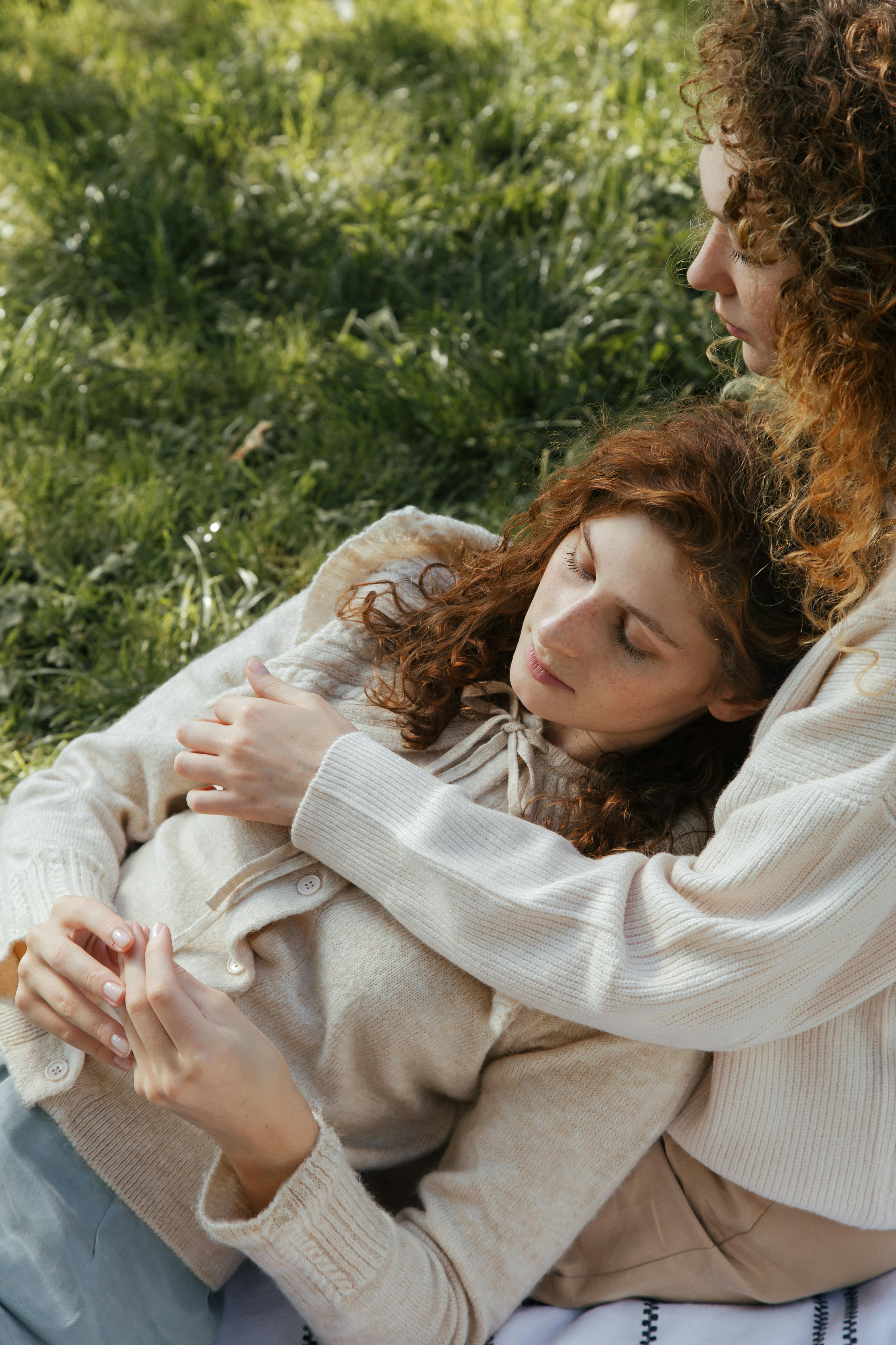 women lying together on grass