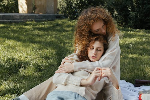 Women Hugging on Blanket on Grass