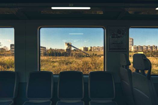Empty train with cityscape view through window, capturing urban and industrial landscapes.