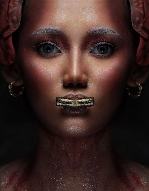 A dramatic studio portrait of a woman with creative face paint and bold visual elements.