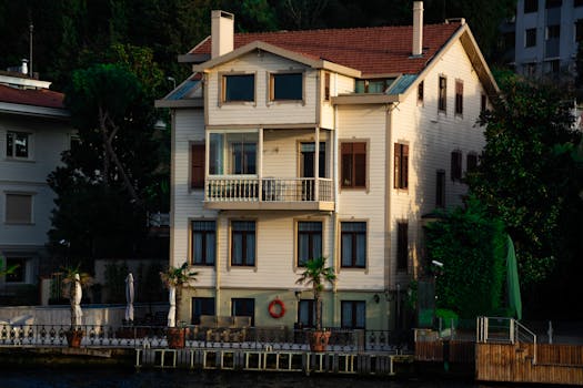 Elegant waterfront house with a classic facade and balcony, captured at sunset.