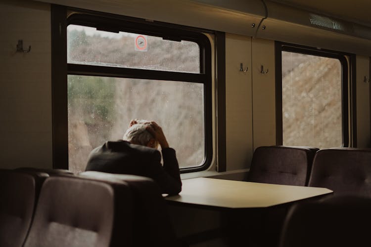 Elderly Man On A Train Sitting By The Table 