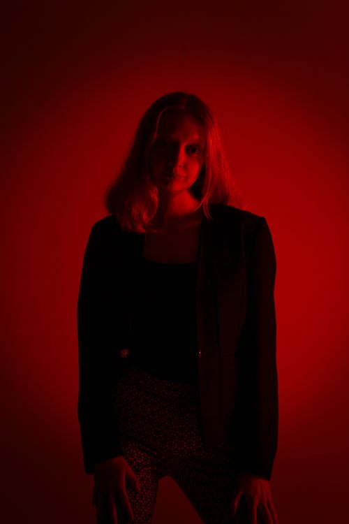 Free A model posing in a black blazer with dramatic red lighting in a studio setting. Stock Photo