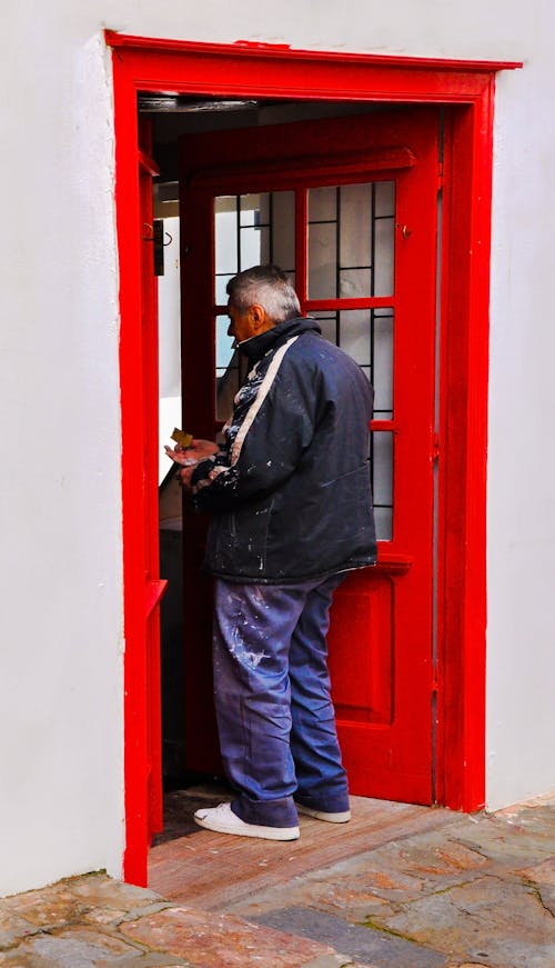 Free Man Standing by a Red Door Stock Photo