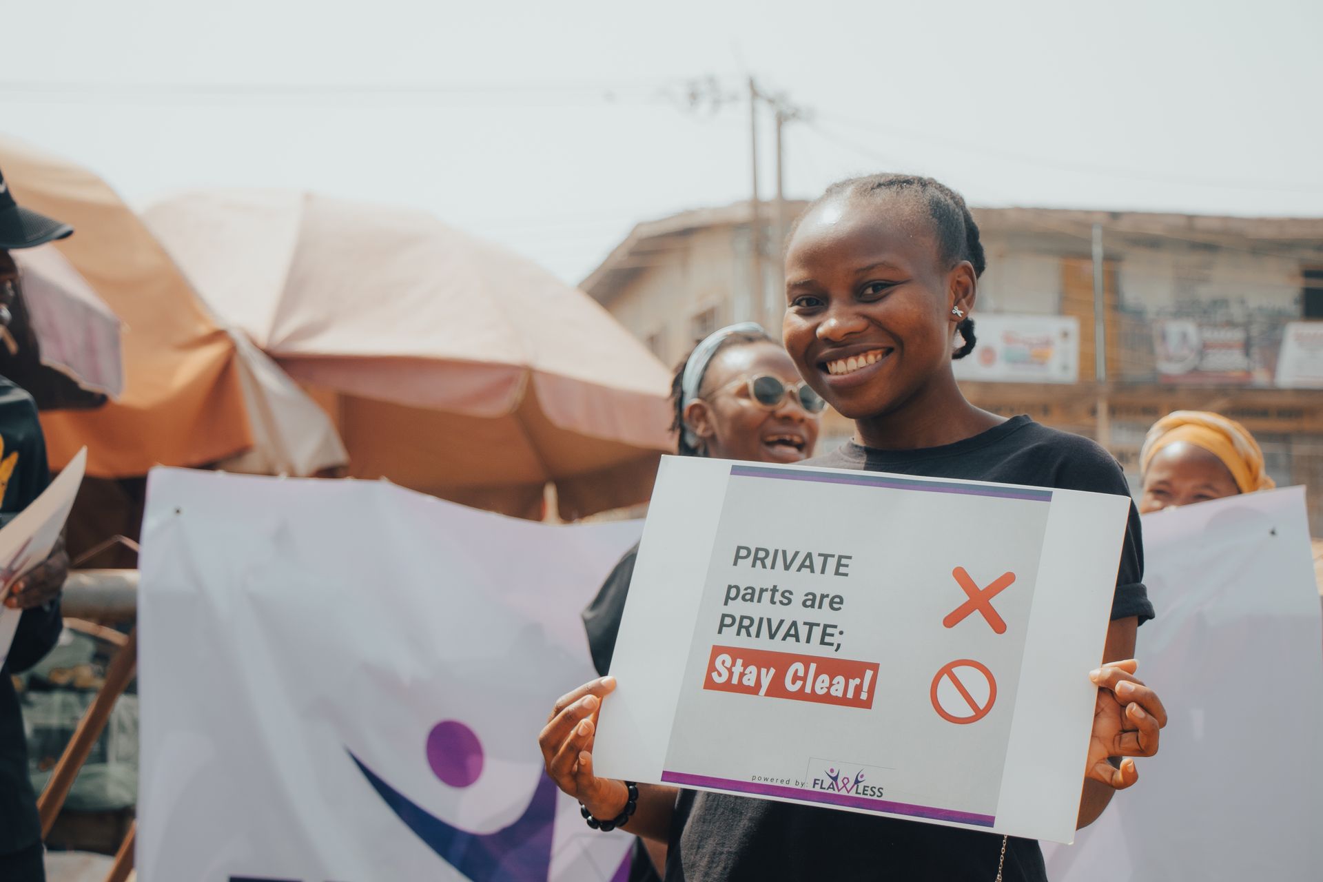 Smiling woman at a demonstration holding a sign advocating privacy rights outdoors.