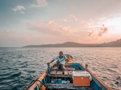 A lone fisherman navigates the calm waters of the Andaman Sea at sunrise, setting out for a day of adventure.