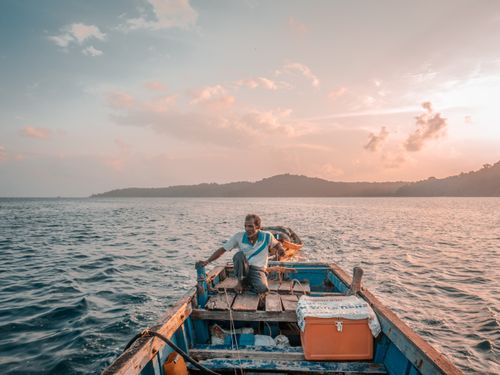 Free A lone fisherman navigates the calm waters of the Andaman Sea at sunrise, setting out for a day of adventure. Stock Photo