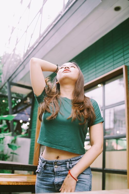 Free Young woman in crop top and jeans posing confidently outdoors in Semarang, Indonesia. Stock Photo