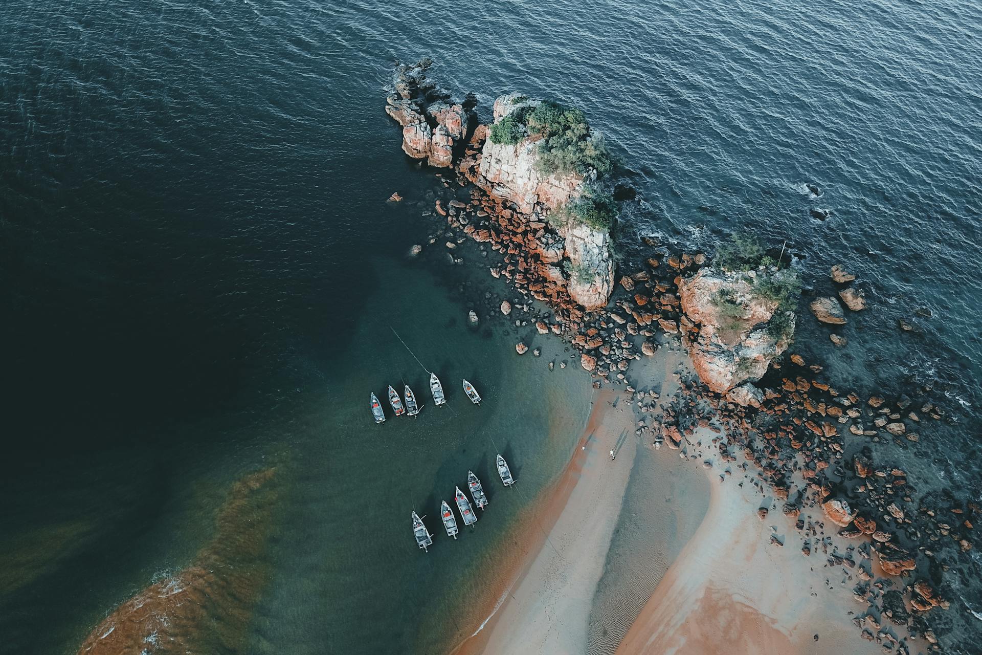 A scenic aerial view shows boats by a rocky coastline, ideal for travel inspiration.