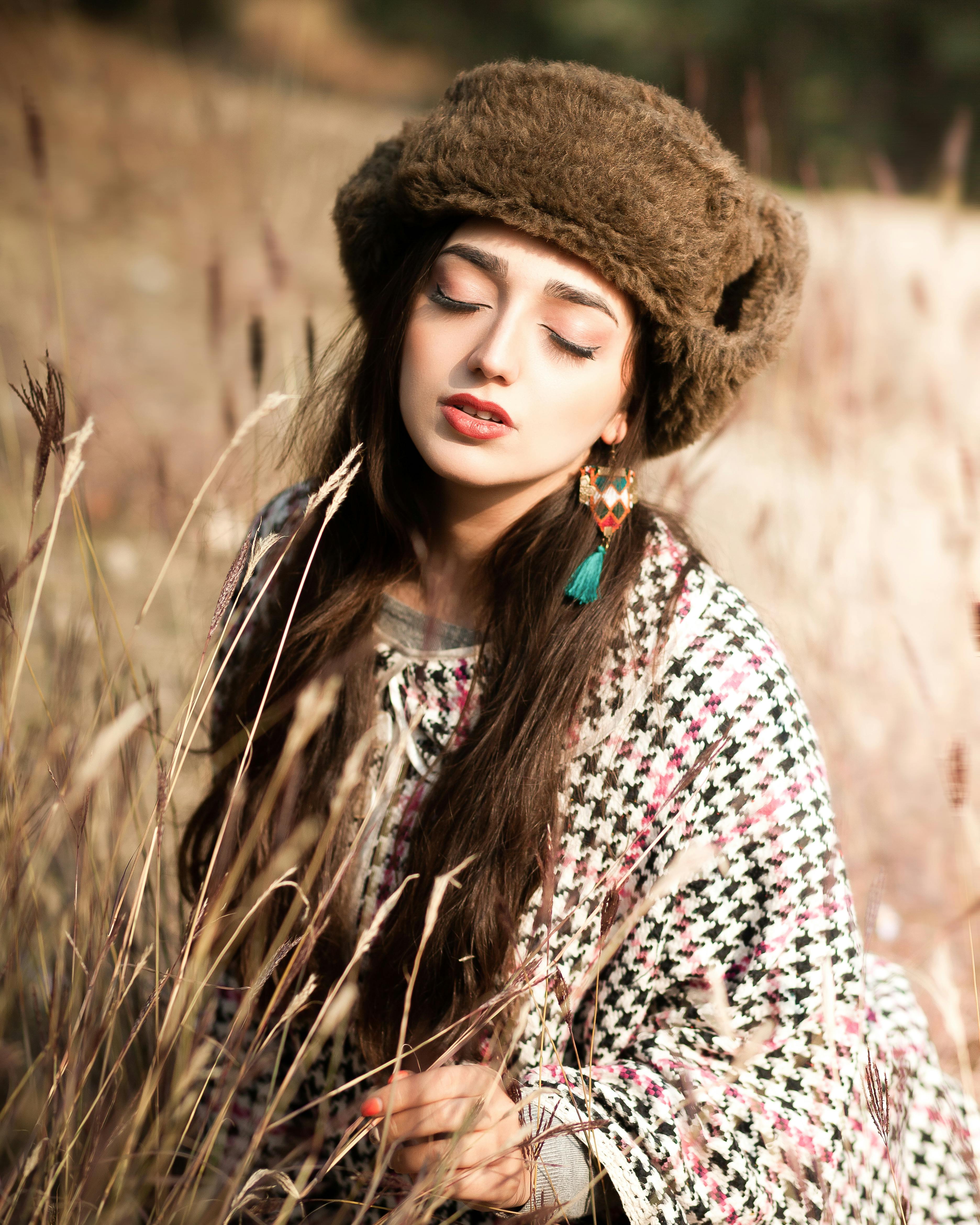 Free A woman wearing a fur hat and poncho in a serene autumn field setting. Stock Photo