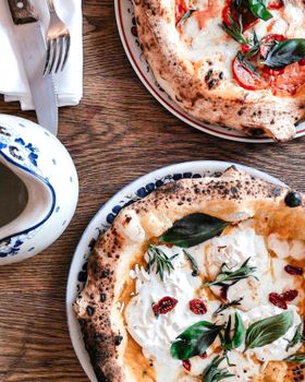 Two delicious Italian pizzas with fresh ingredients on a wooden table.