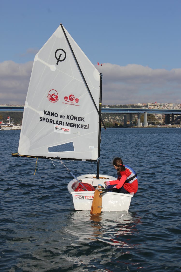 A Girl Wearing Life Vest Sitting On A Sailing Boat