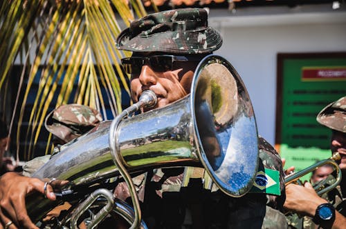 A Man in Camouflage Uniform Playing the Tuba