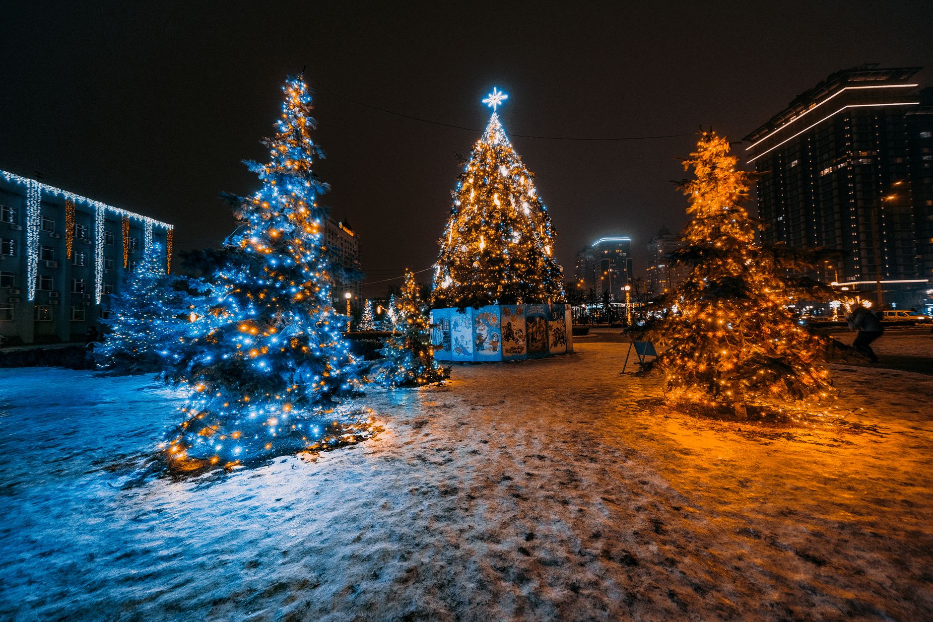 Festive Christmas tree lights in a snowy cityscape at night. — free online jigsaw puzzle on JigsawPuzzlesFreeOnline.org