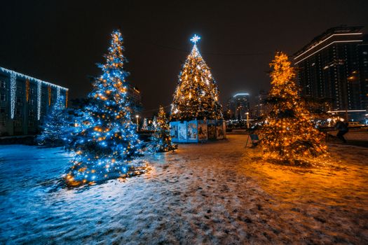 Festive Christmas tree lights in a snowy cityscape at night., free online jigsaw puzzle on JigsawPuzzlesFreeOnline.org